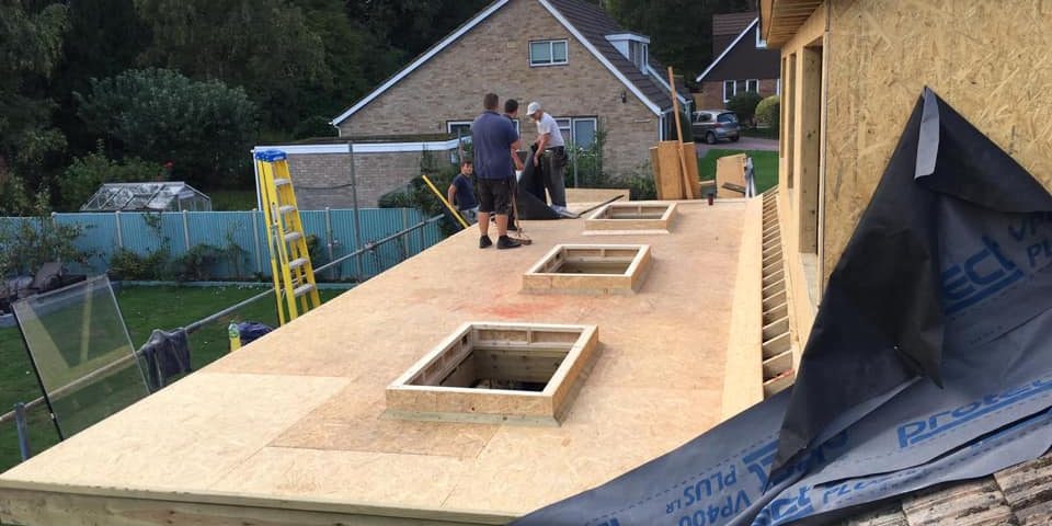 Joiners on top of a flat wooden roof.