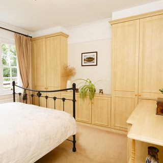 Modern bedroom with neutral colour scheme, cast iron bed and fitted wardrobes