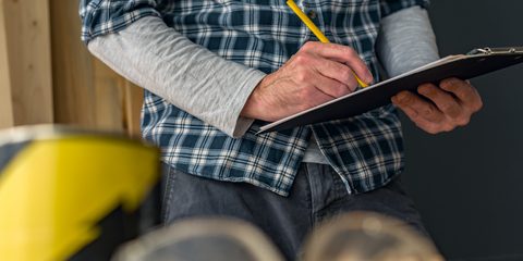 Carpenter writing notes on clipboard notepad