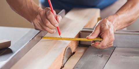 measuring wood at tablesaw in workshop